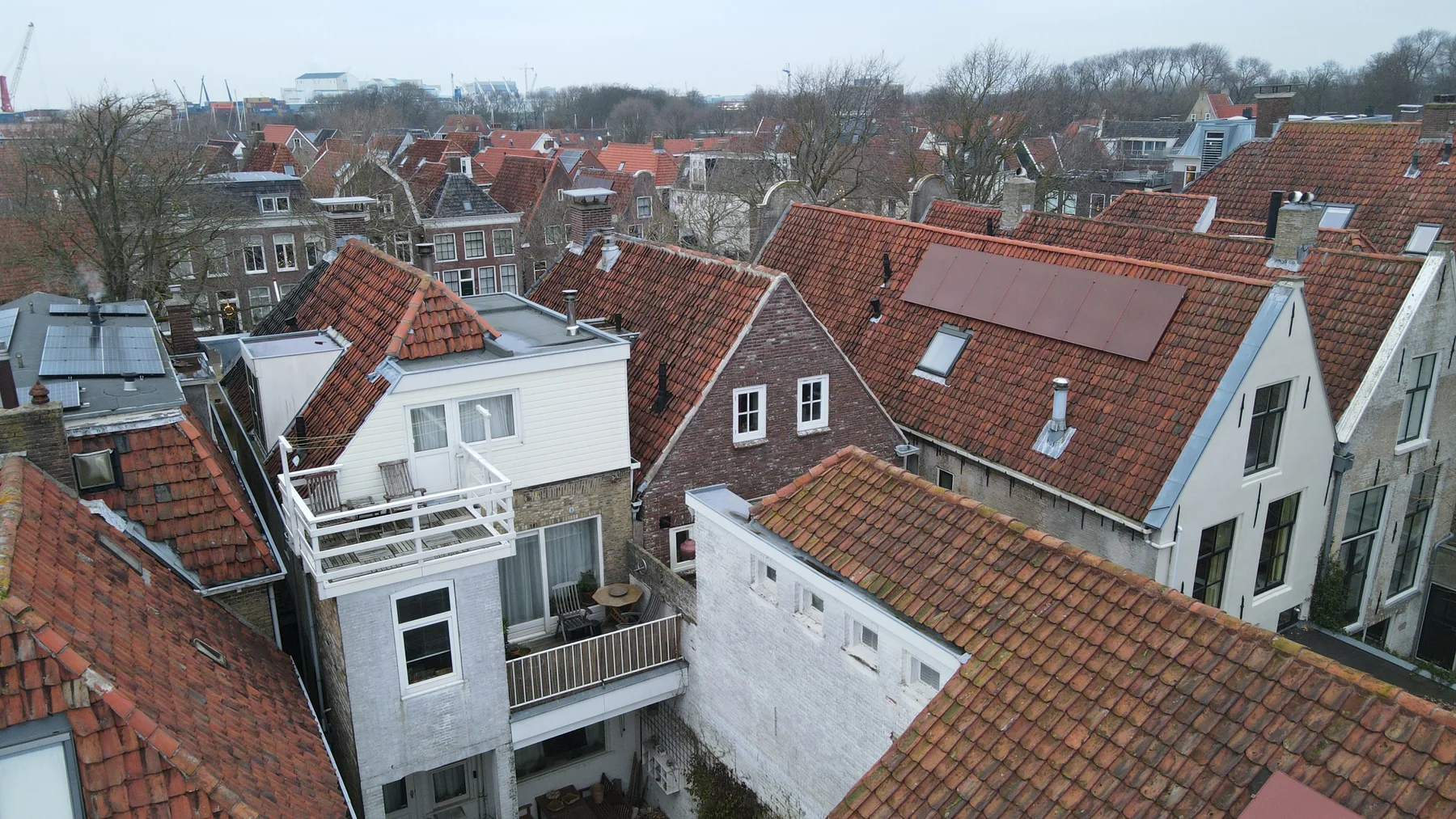 Rode zonnepanelen passend tussen rode pannendaken in een historische omgeving